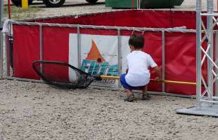 A small child with a fishing net by a Redfish Holding Tank.